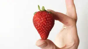 A hand holding a strawberry