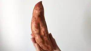A hand holding a sweet potato