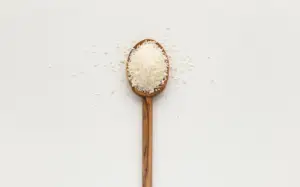 a pile of salt on a wooden spoon against a cream background